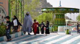 The photo depicts several women, clad in hijabs, walking along a path in a recreational park in Kabul with their children