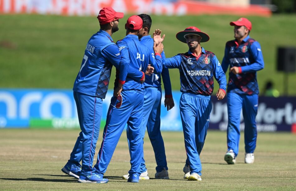 The photo captures several players of Afghanistan's under-19 cricket team celebrating a victory on the field.