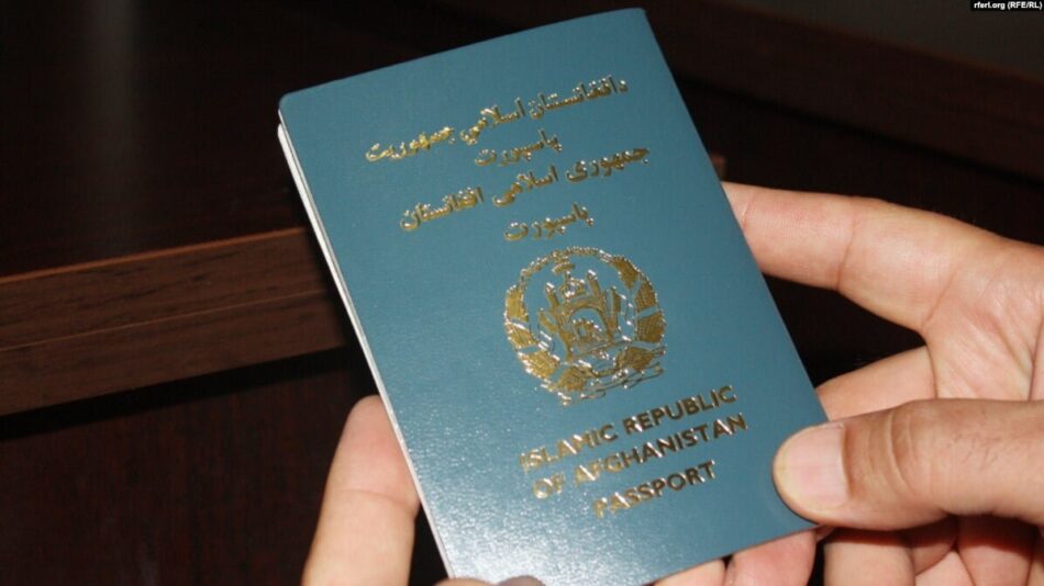 The photo features an Afghan passport held in the hands of an individual.