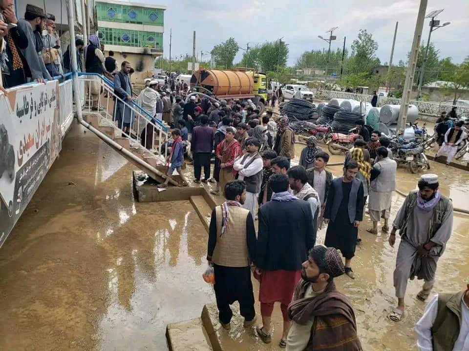 A crowd of people assemble at a market in Ghor province after severe floods. Many are standing and watching the damage caused by the flood. 