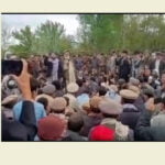 Photo of community leaders speaking at a public gathering during protests in Badakhshan, with people gathered around them. The image is a screenshot from a video shared on social media
