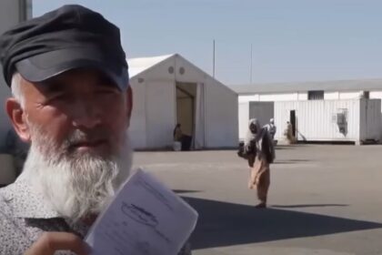 An elderly Afghan worker at the Islam Qala border between Iran and Afghanistan holds up a work permit he received in Iran. He explains to reporters that Iranian authorities forcibly deported him, leaving his wages for several months unpaid by his employer.