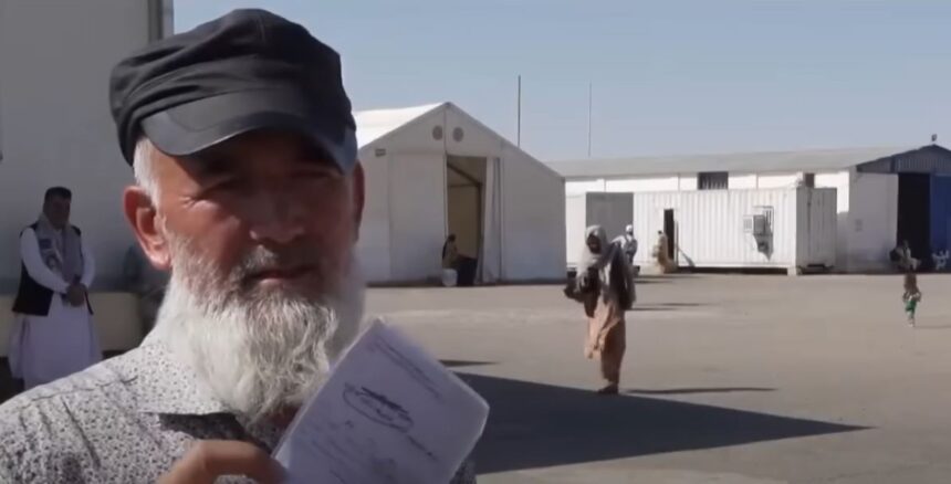 An elderly Afghan worker at the Islam Qala border between Iran and Afghanistan holds up a work permit he received in Iran. He explains to reporters that Iranian authorities forcibly deported him, leaving his wages for several months unpaid by his employer.